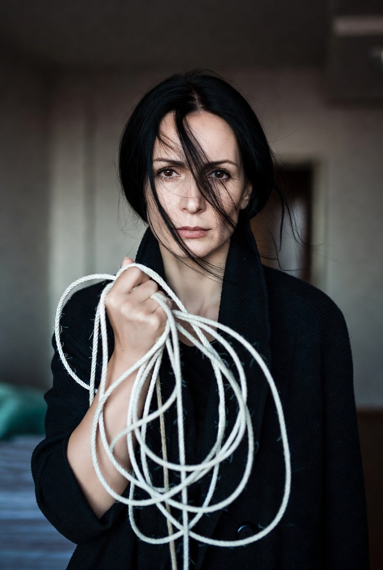 Donna che guarda l'obiettivo con corde slegate in pugno - Foto realizzata con xAI