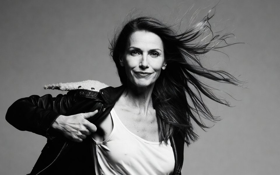 Donna adulta che si toglie la giacca in un movimento deciso, fotografia in bianco e nero